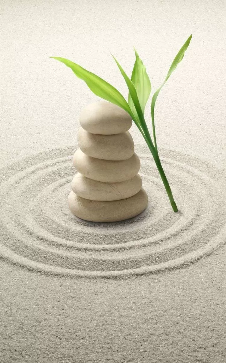 Rocks balancing in a circle of sand.