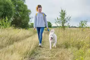 Woman walking her dog gaining experiencing the benefits of exercise.
