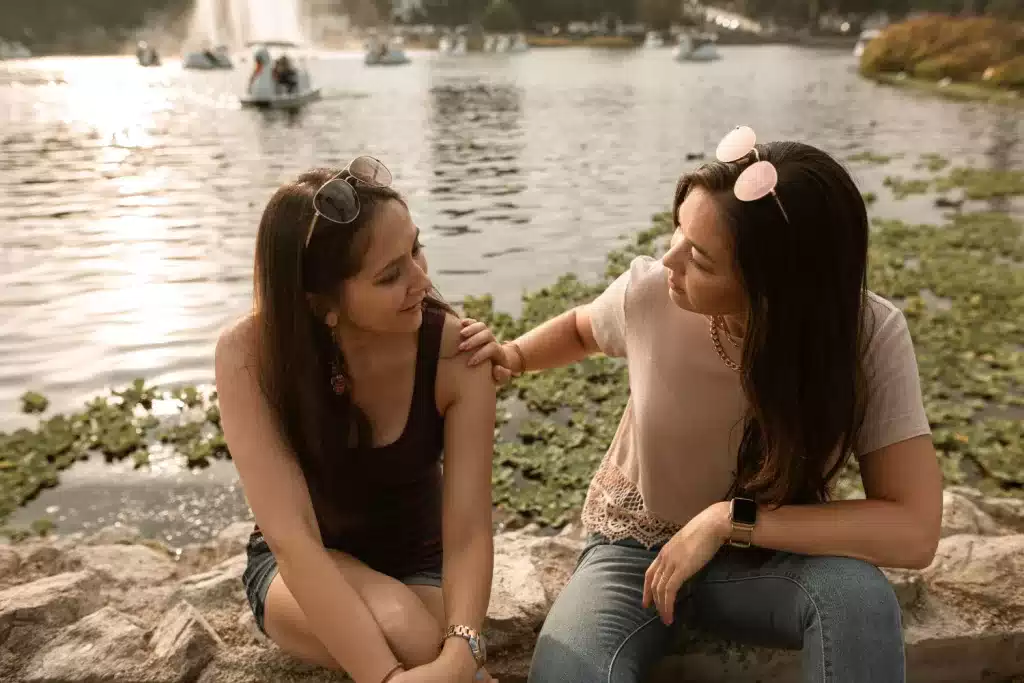 Women talking to a loved one, by the water