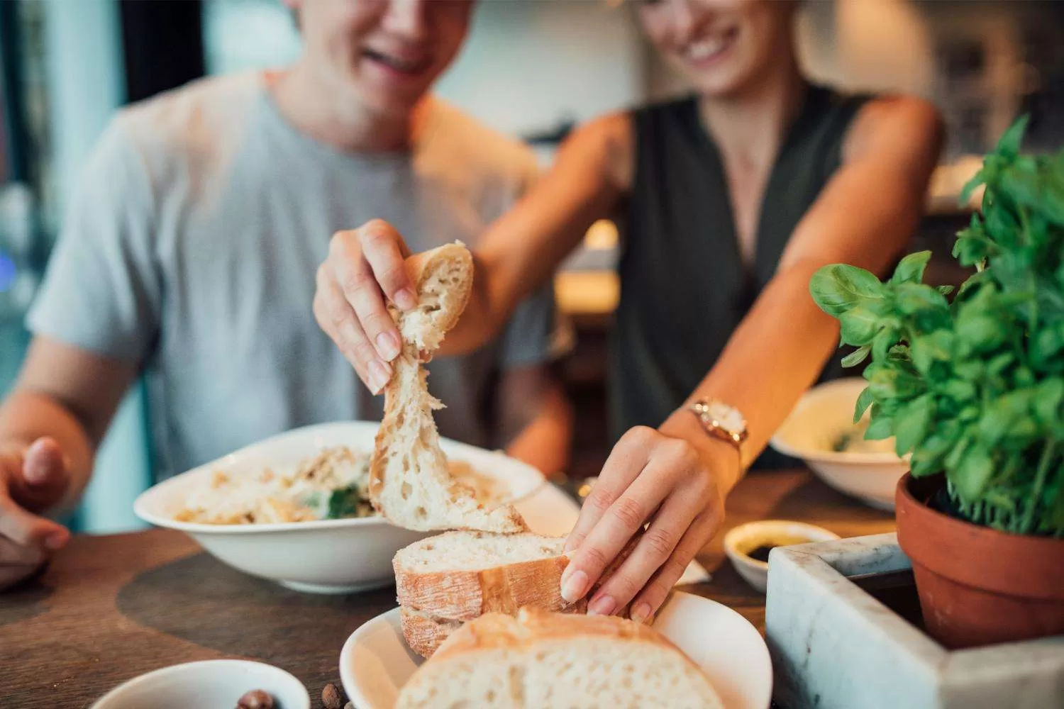 Couple reaching for bread and enjoying their food.