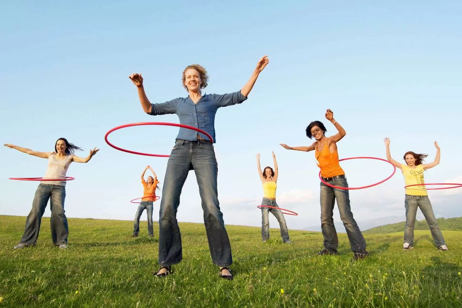 Several woman enjoying movement in the park by hula hooping.