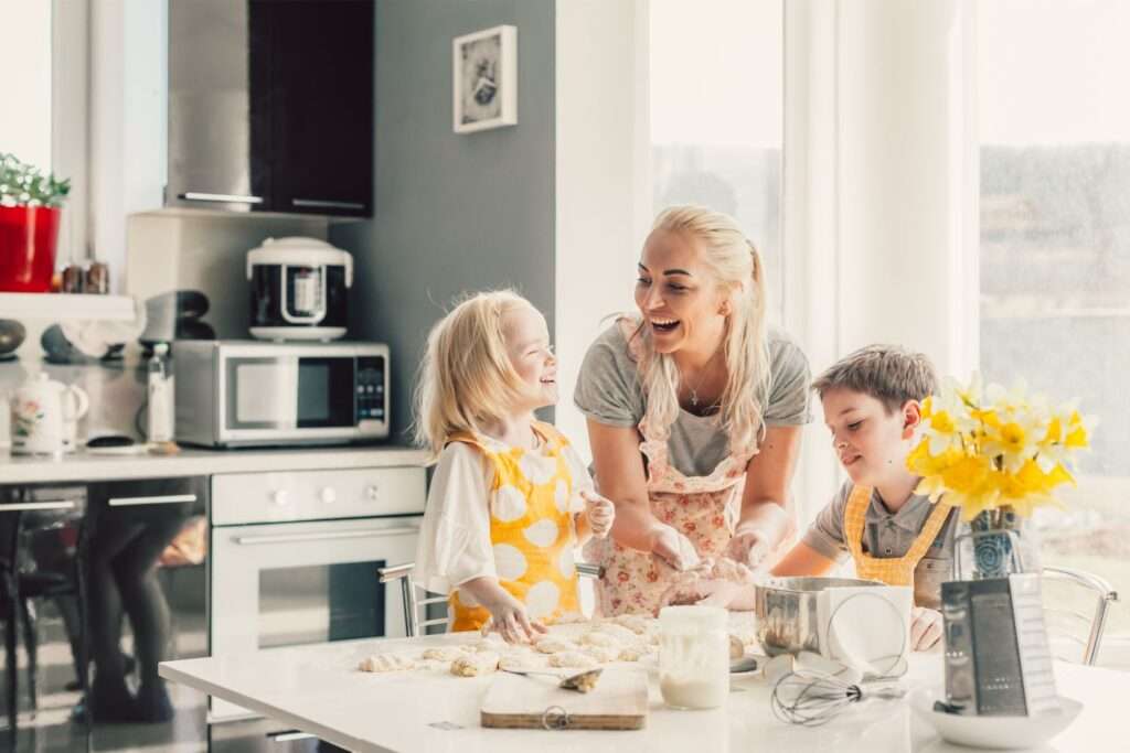 Mom creating food memories with her two children by baking in the kitchen.