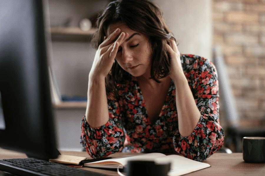 Understanding POTS - Woman sitting at Desk Holding her Head