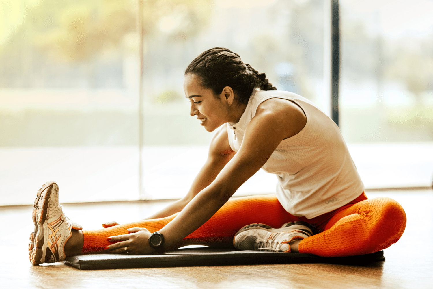 A woman stretching on a yoga mat, highlighting the importance of listening to your body and noticing body signals during exercise, moving in ways that feel supportive and gentle.